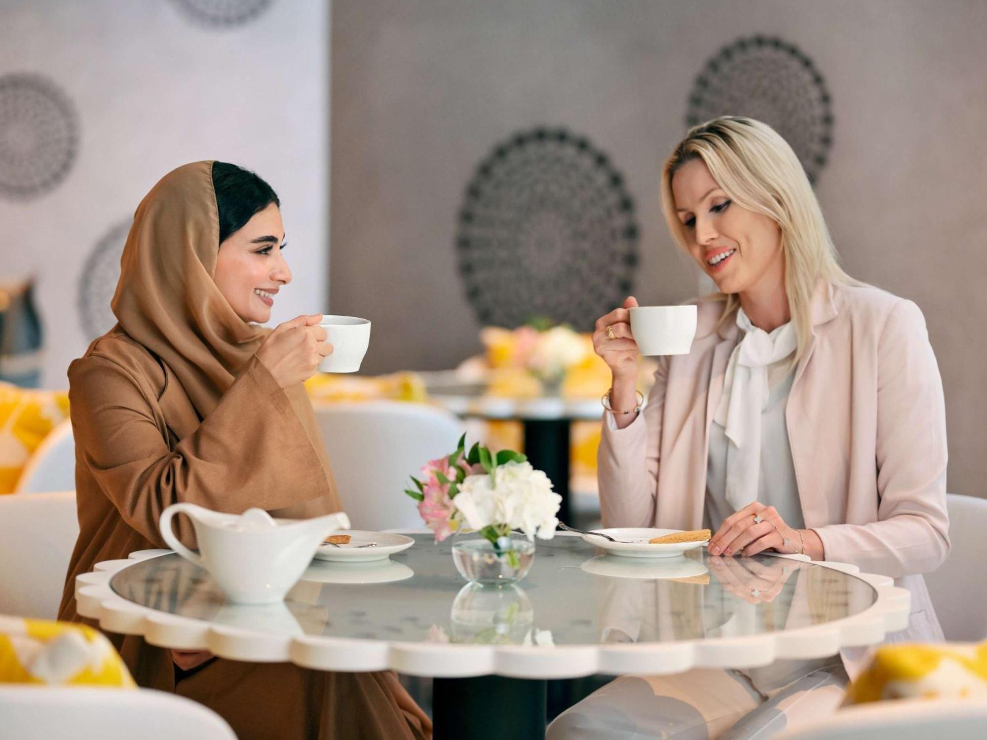 Moevenpick Hotel & Apartments Ghala Mascate Exterior foto Two women drinking coffee